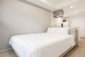 A modern hotel room with a large bed, a bedside table, a built-in heater, and a wall-mounted TV. - MoriKoYa Hotel · 2BR Deluxe 45m² · Senso-ji 5 min (Taito City)