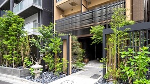 Moderni rakennus, jossa on parveke, ja sen ympärillä on hyvin hoidettua viheraluetta sekä kivipolku.