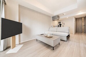 A modern living room with a flat-screen TV, a sofa, a coffee table, and a kitchen area in the background. - MoriKoYa Hotel · 2BR Deluxe 45m² · Senso-ji 5 min (Taito City)