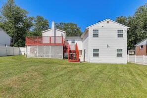 Una casa de dues plantes amb terrassa vermella i tanca blanca.