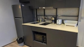Una cocina compacta con horno integrado, cafetera y tostadora sobre la encimera.