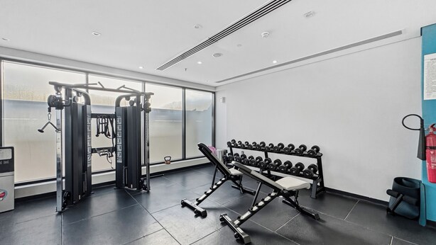 Ett modernt gym med träningsutrustning, en bänk och hantlar.