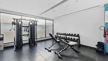Academia moderna com equipamentos de exercício, um banco e halteres.