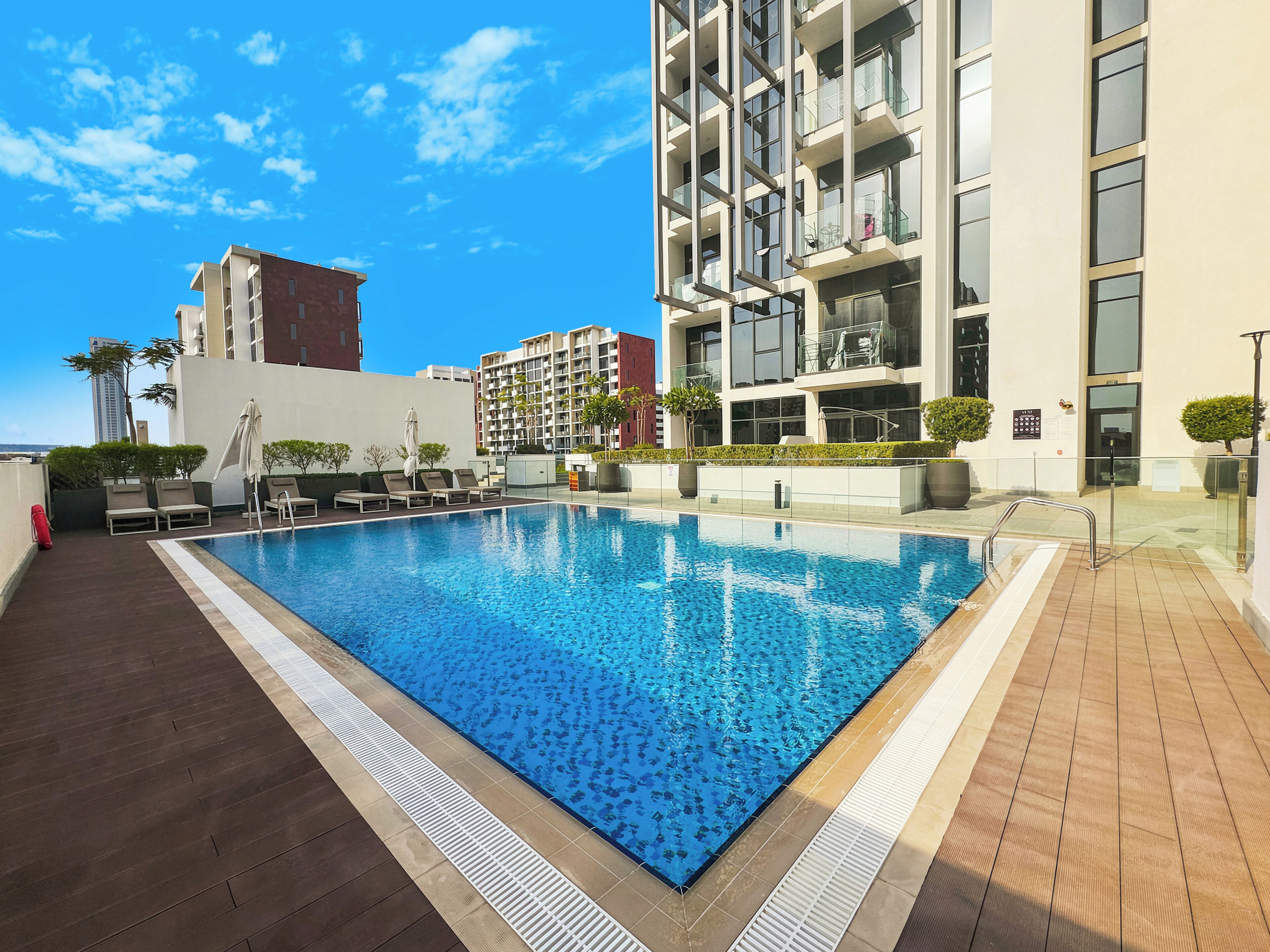 A swimming pool with lounge chairs and a view of modern buildings.