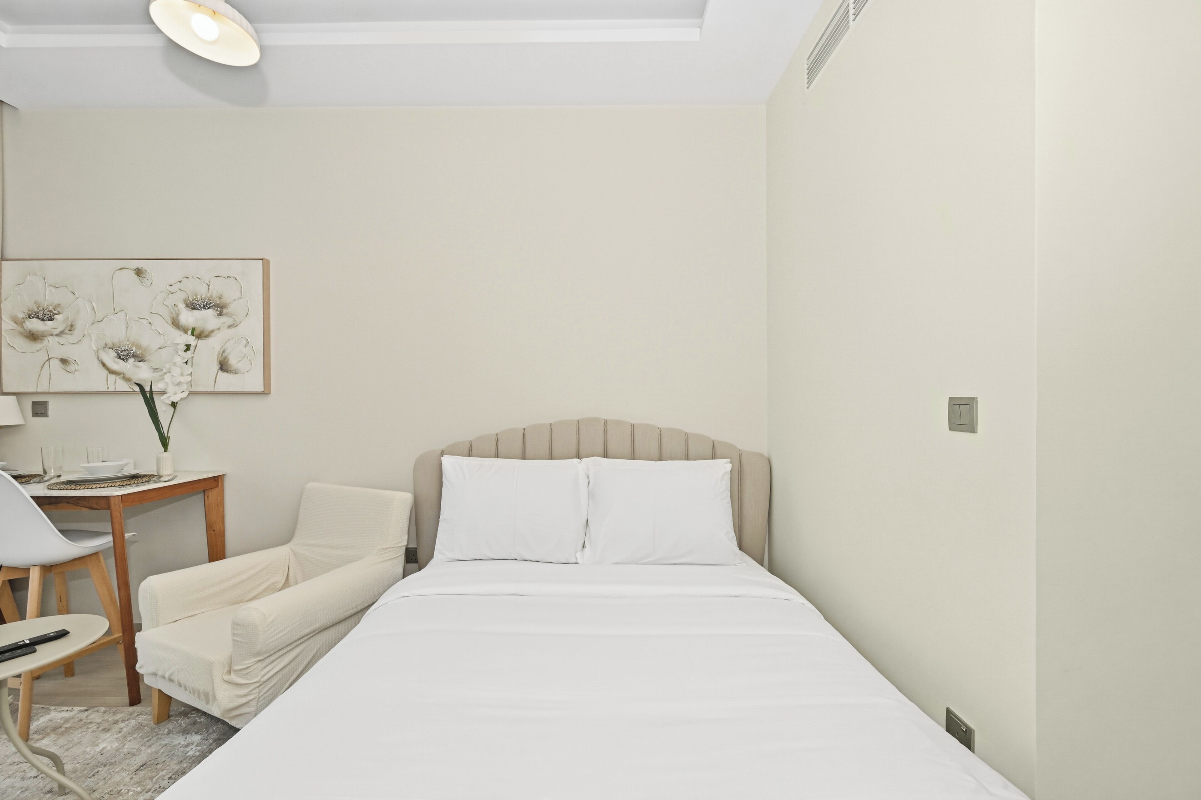 Une chambre d’hôtel avec un lit, une chaise, une petite table et une œuvre d’art accrochée au mur.