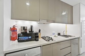 Eine moderne Küche mit eingebautem Geschirrspüler, einem Gasherd und einer Kaffeemaschine.