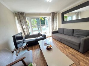 A modern living room with a sofa, a coffee table, and a TV. - Euston Square 2 Bed Apart (Greater London)