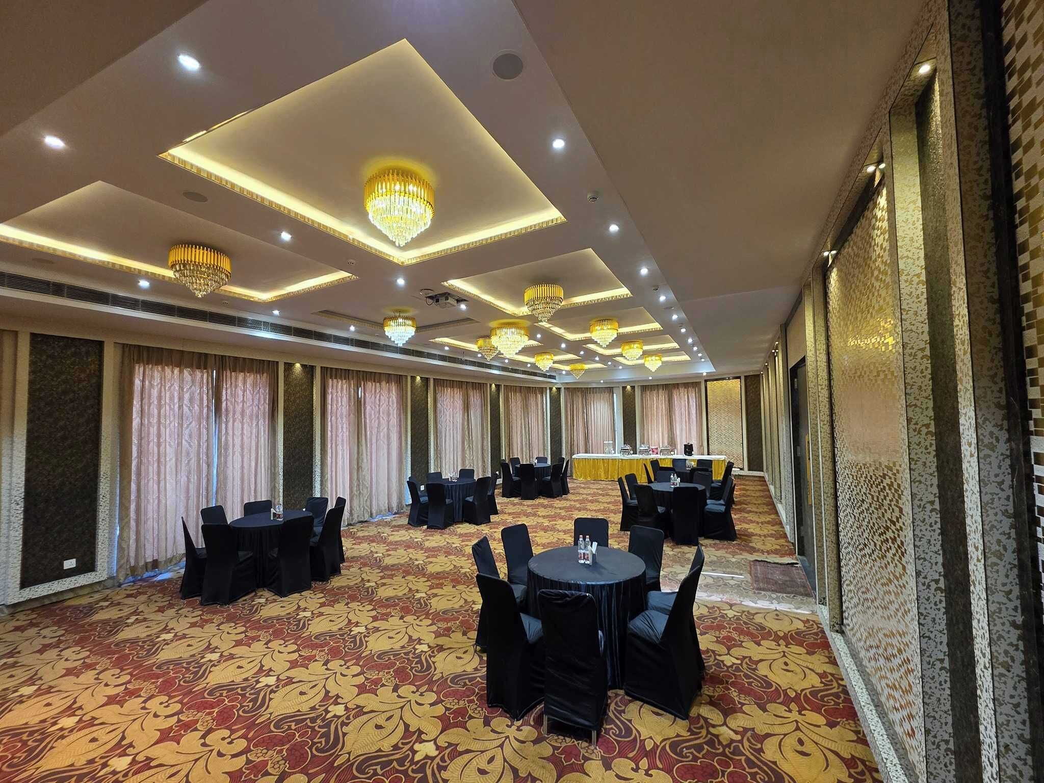 A conference room with tables and chairs, a patterned carpet, and chandeliers.
