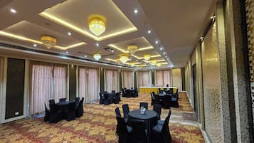 A conference room with tables and chairs, a patterned carpet, and chandeliers.