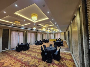 A conference room with tables and chairs, a patterned carpet, and chandeliers.