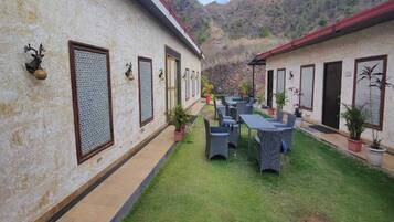 A courtyard with a dining area, two-story buildings, and a mountainous backdrop.