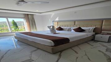 A hotel room with a large bed, a nightstand, a ceiling fan, and a view of the outdoors.