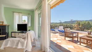 Ein Balkon mit Blick auf die Landschaft, einem Fernseher und einer überdachten Sitzgelegenheit.
