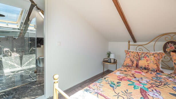 Ein Schlafzimmer mit einem Bett, einem Nachttisch, einem Fenster mit Blick und einer Tür, die auf einen Balkon führt.