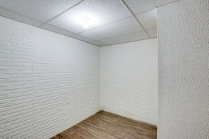Ein Zimmer mit weißen Backsteinwänden, Holzdielenboden und einer strukturierten weißen Wand auf der rechten Seite.