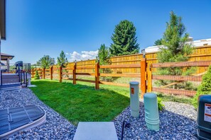 Un espacio exterior cercado con una terraza de madera, una parrilla de metal y un sendero de grava.