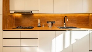 Uma cozinha moderna com painel atrás do fogão em madeira, fogão embutido, pia e cafeteira.