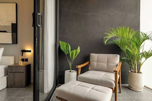 Un salon moderne avec un canapé, un fauteuil et deux plantes en pot.