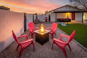 A patio with a fire pit, four red chairs, and a house in the background. - Desert Retreat w/ Pool Near Dtwn Tempe & ASU (Tempe)