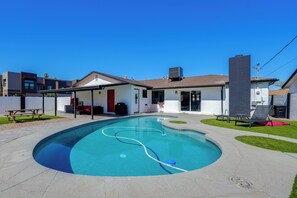 Un jardin arrière d’une maison, comprenant une piscine, un patio couvert et une petite pelouse.