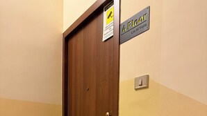 Una puerta de madera con un felpudo que muestra un paisaje. Un letrero encima de la puerta indica el número de habitación '4 FLOOR' y el nombre 'Liu Ai Viale'.