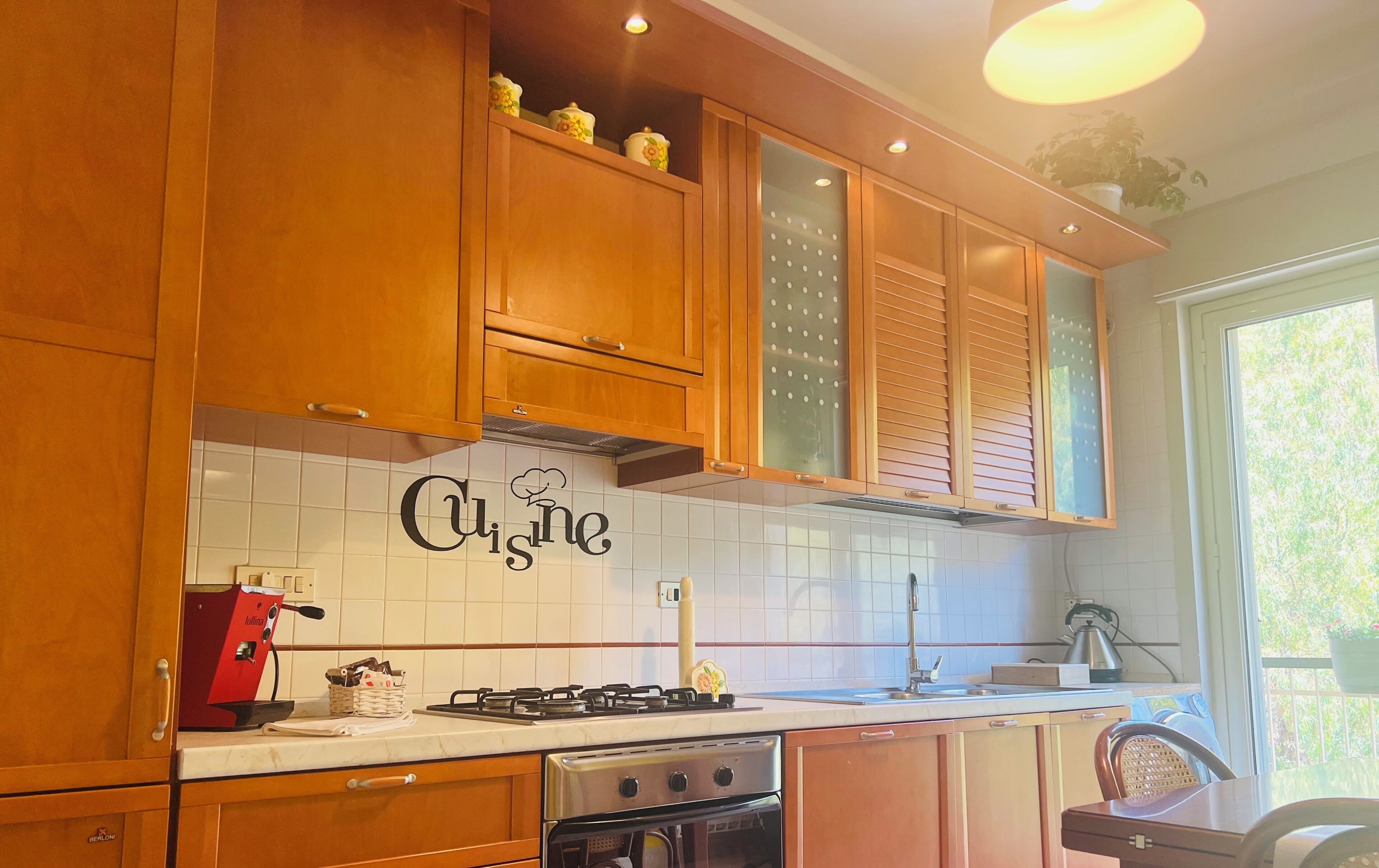 Una cocina con armarios de madera, una estufa a gas, un horno y un salpicadero con la palabra "Cuisinart".