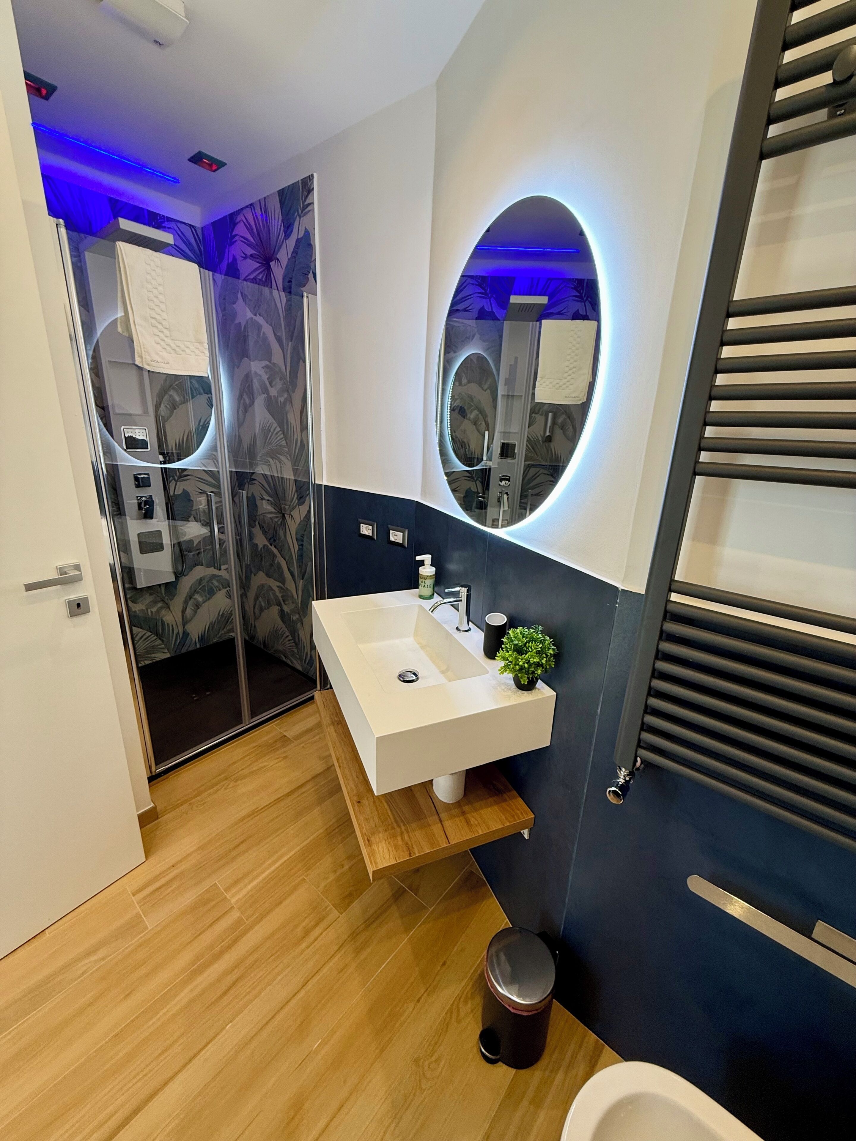 A modern bathroom with a white sink, a mirror with a circular frame, and a shower area with a glass door.