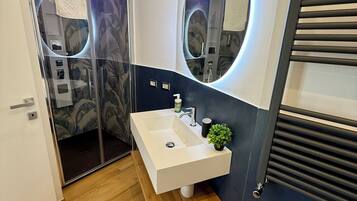 A modern bathroom with a white sink, a mirror with a circular frame, and a shower area with a glass door.