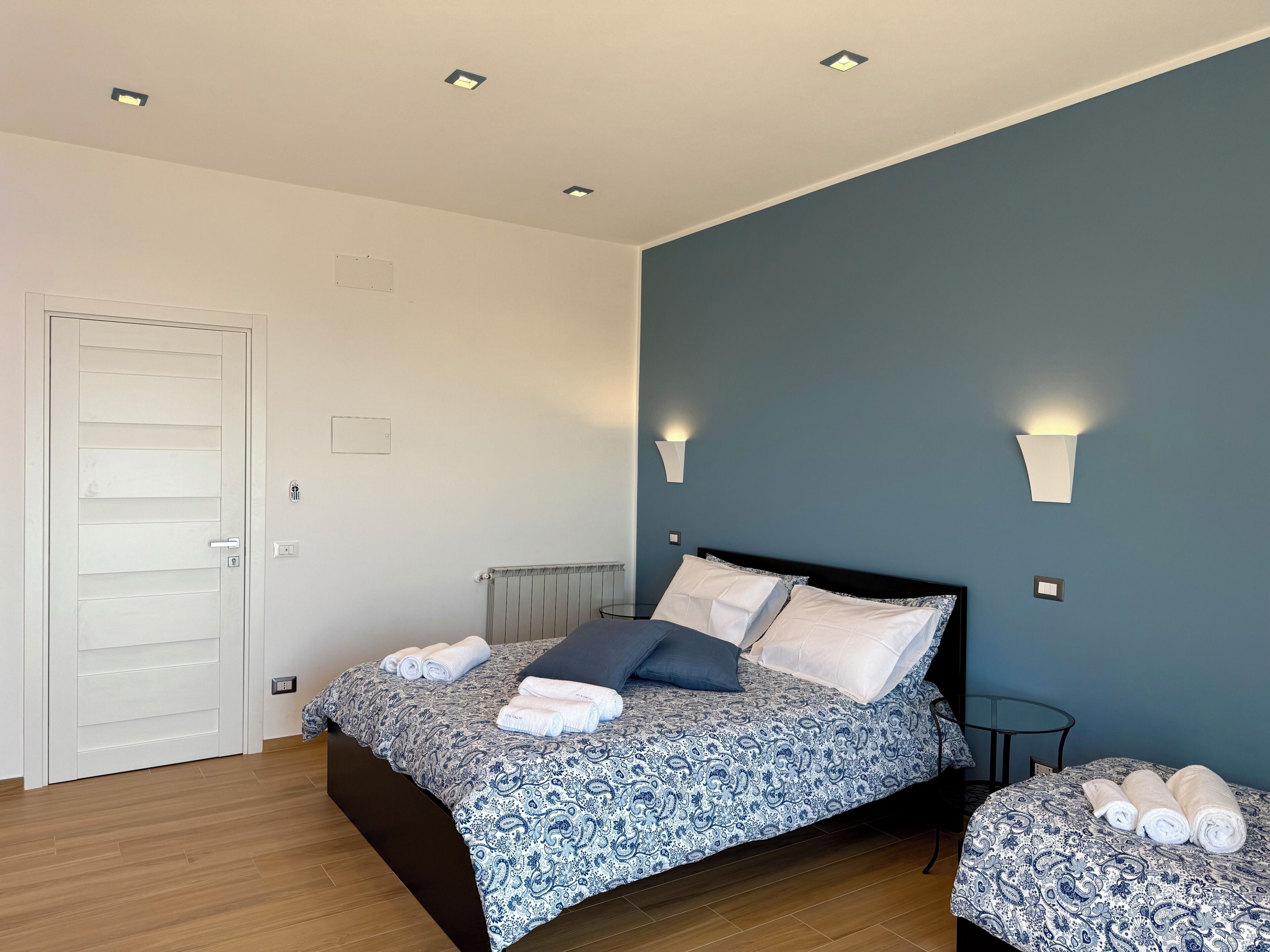 Une chambre à coucher avec un lit, des tables de chevet, un radiateur et une porte.
