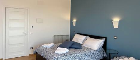 A bedroom with a bed, bedside tables, a radiator, and a door.