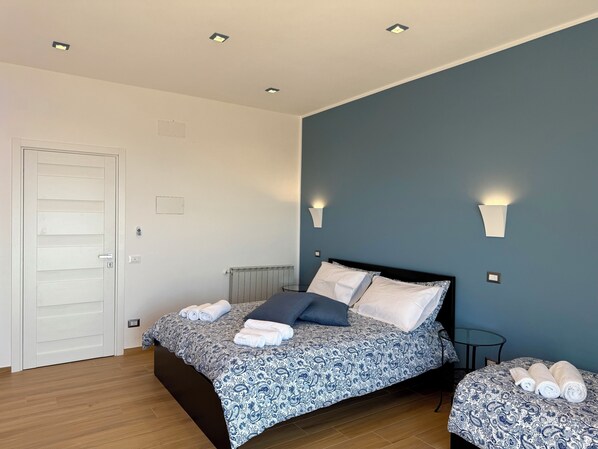 A bedroom with a bed, bedside tables, a radiator, and a door.