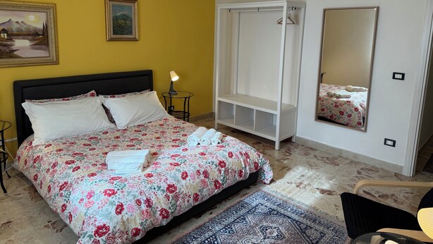Un dormitorio con cama, armario, espejo y mesita de noche.