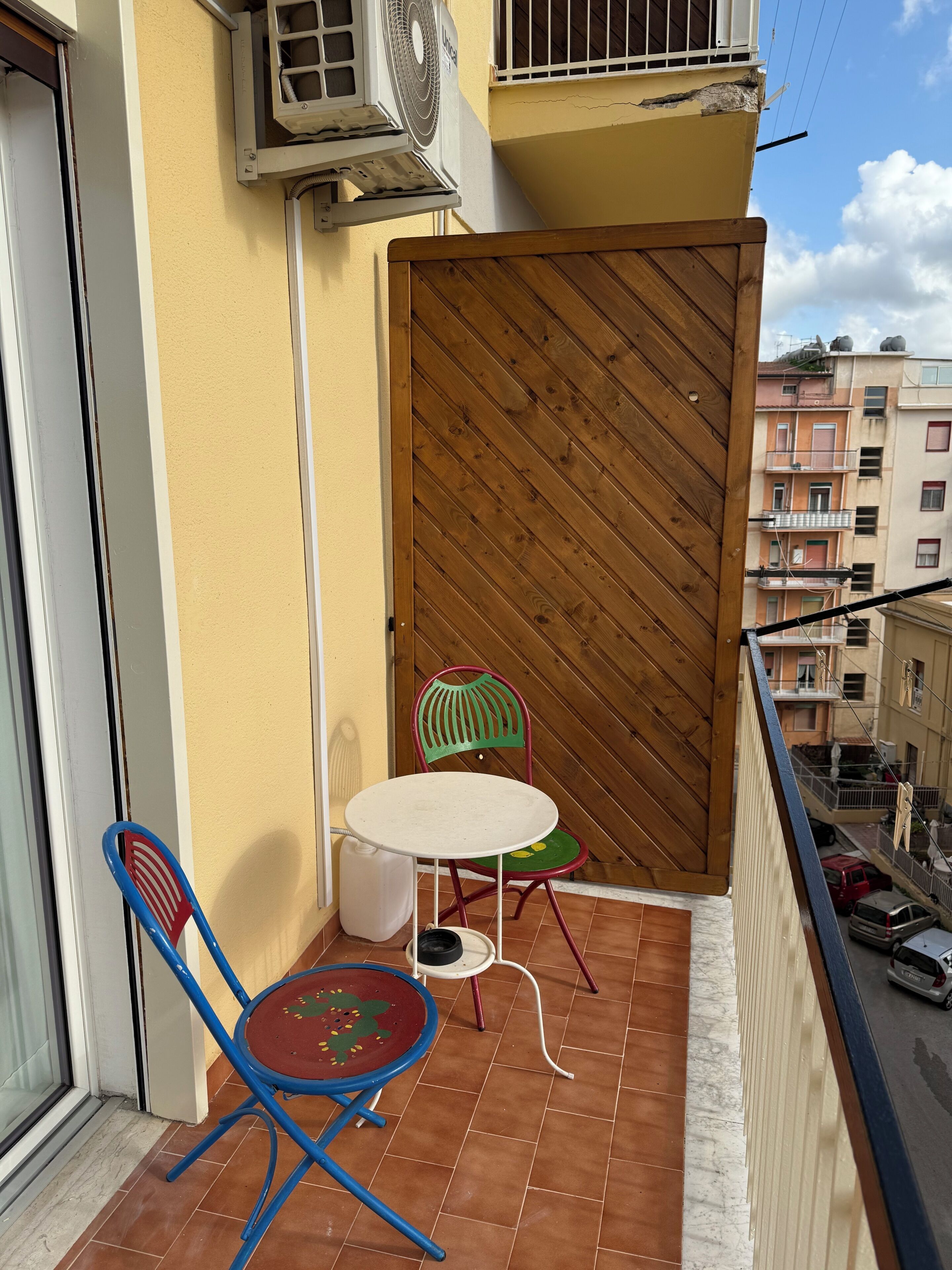 Ein Balkon mit einer Holztür, einem kleinen Tisch und zwei Stühlen.