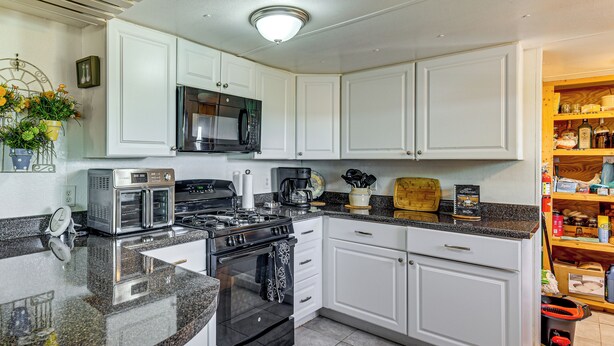 A kitchen with white cabinets, a microwave, a stove, and a coffee maker. - On Deer Point Lake! Home w/ Private Dock & Hot Tub (Youngstown)