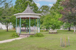 Ein Kiosk mit spitzer Kuppel, umgeben von Gras und Bäumen.