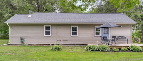 A single-story house with a front porch, a chimney, and a small deck with outdoor furniture.