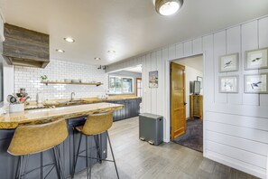 Cocina con barra, salpicadero de azulejos blancos y detalles de madera.