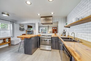 Eine moderne Küche mit Kochinsel, Edelstahlgeräten und einer Holz Arbeitsplatte.