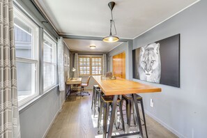 Eine moderne Küche mit einem langen Holztisch, Barhocker und einem großen Fenster mit Vorhängen.