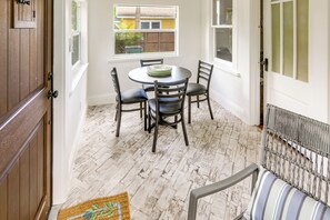 A dining area with a round table and four chairs, a wooden door, and a view of a house through a window. - Walk to Lakeworth Dtwn! 5-Min Drive to Beach (Lake Worth Beach)