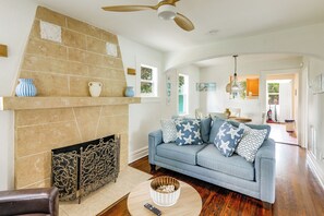 A living room with a fireplace, a sofa with star-patterned cushions, and a dining area in the background. - Walk to Lakeworth Dtwn! 5-Min Drive to Beach (Lake Worth Beach)