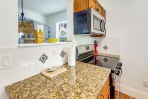 Une cuisine dotée d’un plan de travail en granit, d’appareils électroménagers en acier inoxydable et de carreaux décoratifs.