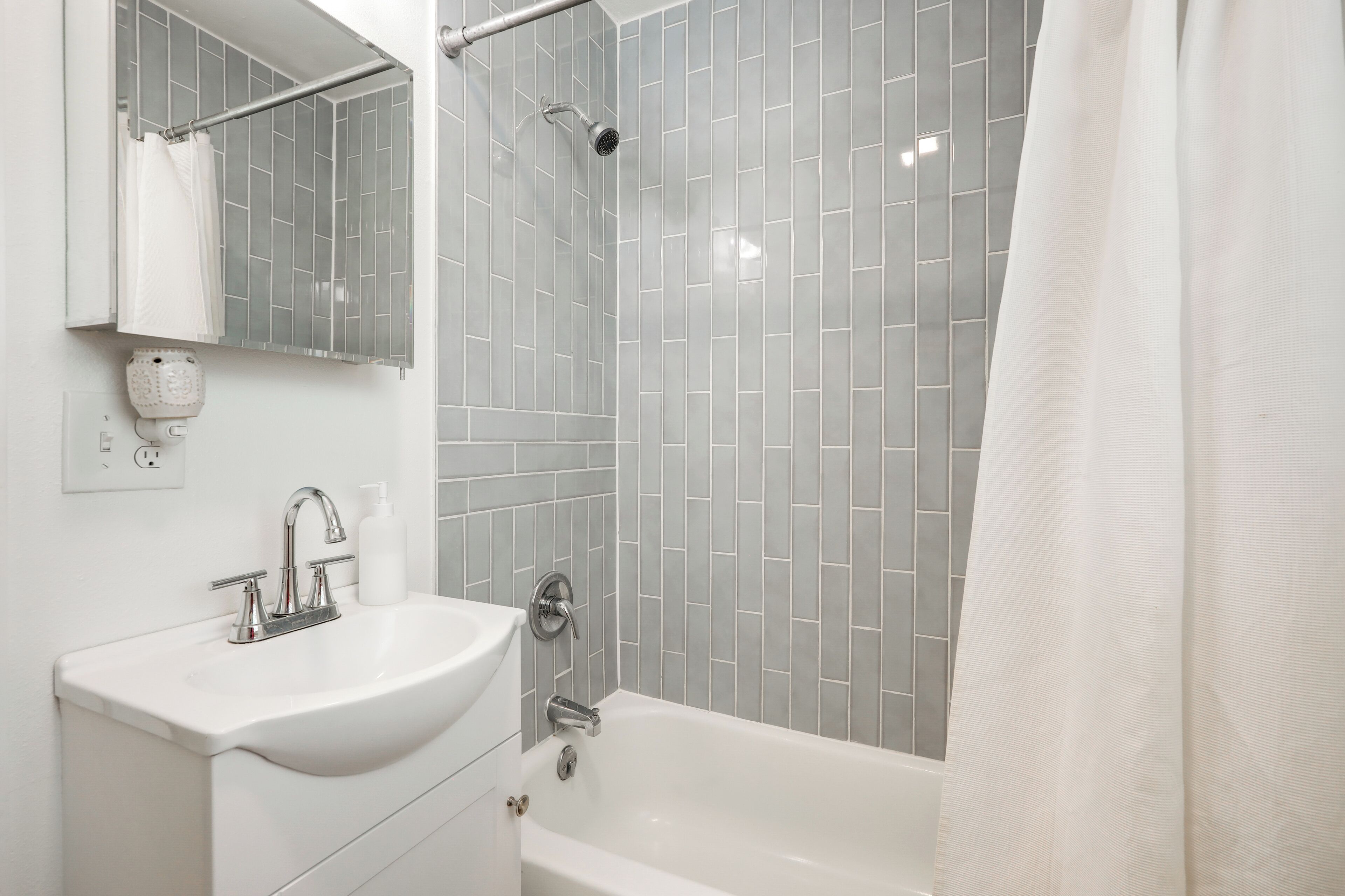 Ein modernes Badezimmer mit einem weißen Waschbecken, einer Dusche und einer Badewanne.