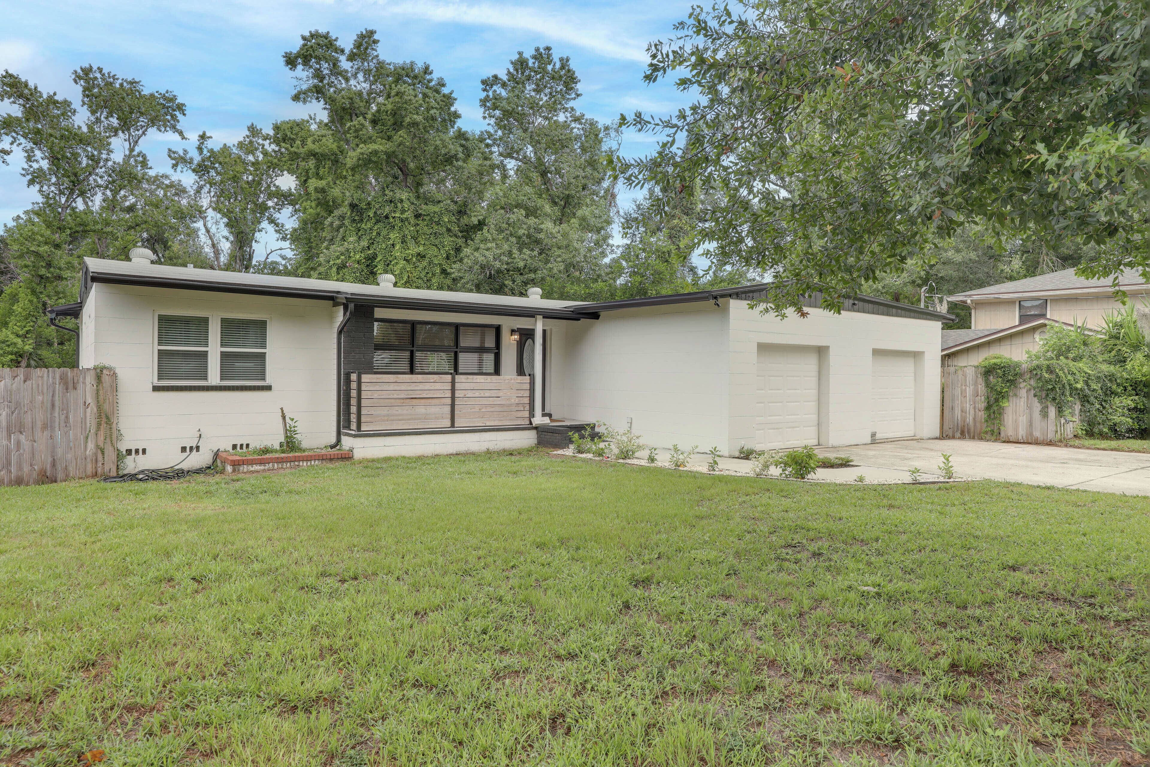 A single-story house with a garage, a small front yard, and a wooden fence.
