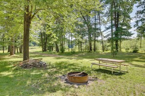 Ein Picknicktisch und ein Lagerfeuer in bewaldeter Landschaft.