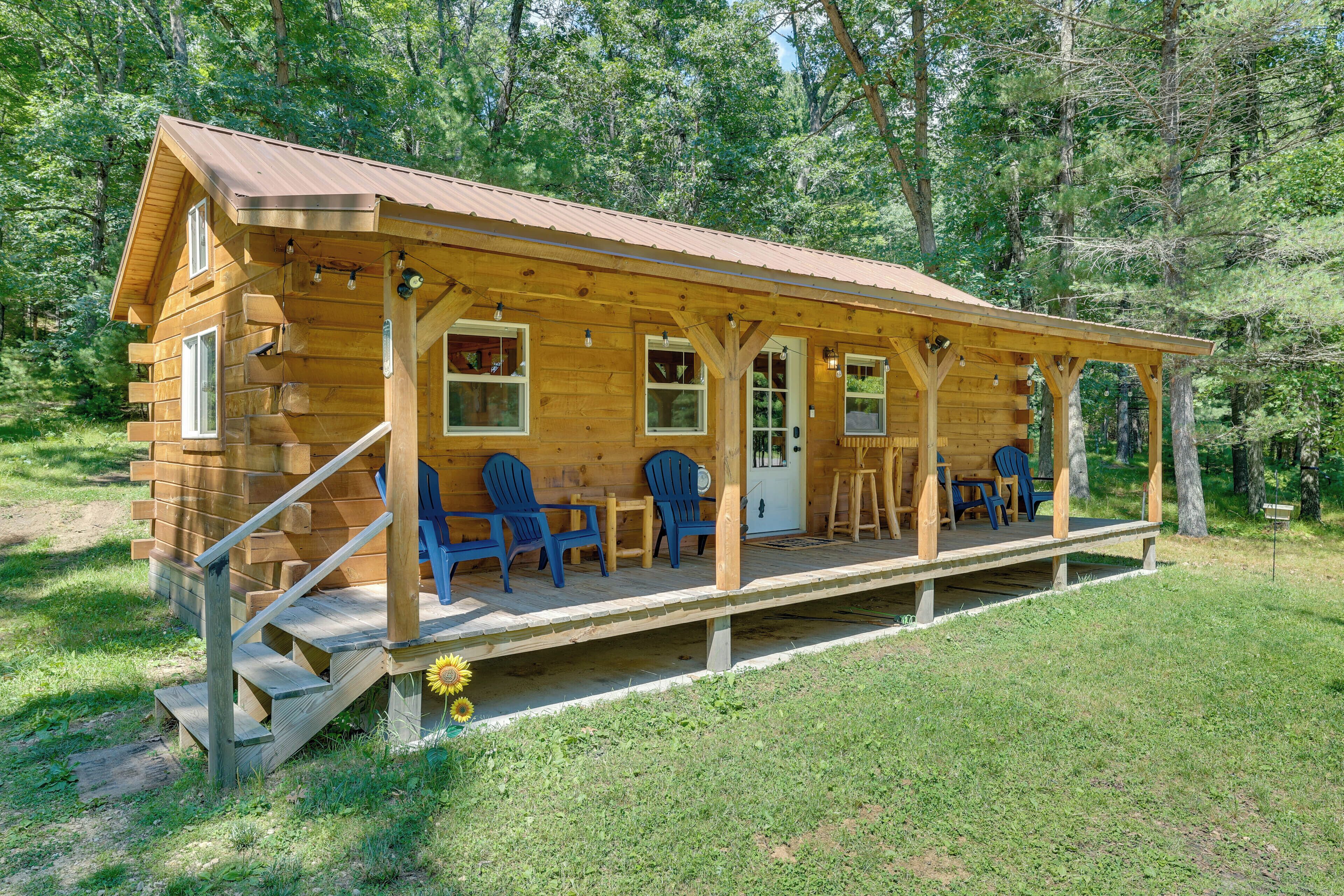 A log cabin with a porch, outdoor seating, and a staircase leading to the entrance.