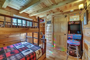 Eine Hütte mit Etagenbetten, einer kleinen Küchenzeile und einer Tür zu einem Abstellraum.