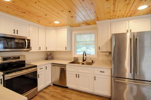 A modern kitchen with white cabinets, stainless steel appliances, and a wooden ceiling. - Boater’s Retreat on Lake Greenwood! 1 Mi to Marina (Cross Hill)