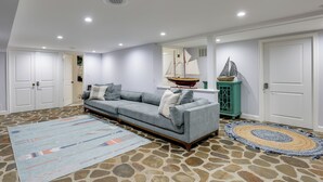 A living room with a sofa, a rug, a ship model, and a stone-patterned floor. - Waterfront Gem w/ Dock: 2 Mi to Dwtn Annapolis! (Annapolis)