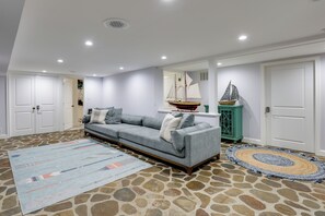 Ein Wohnzimmer mit einer Couch, einem Teppich, einem Schiffmodell und einem Steinmuster-Boden.